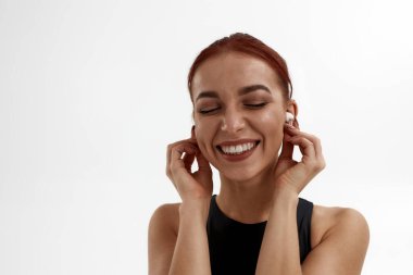 Neşeli beyaz kadın kulaklıkla müzik dinliyor.