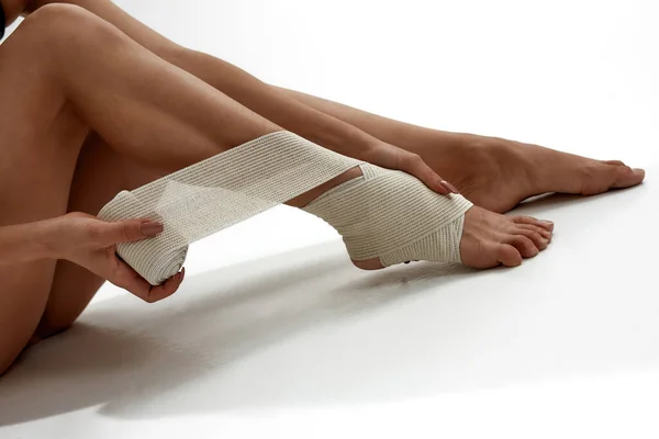 Cropped of girl putting elastic bandage on leg — Stock Photo, Image