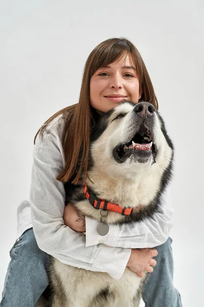 Ευρωπαϊκή κοπέλα αγκαλιάζει σκύλο σε λευκό στούντιο — Φωτογραφία Αρχείου