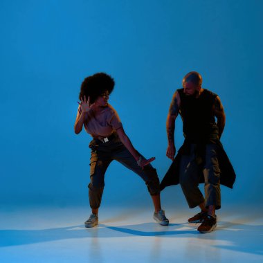 Dans eden çift mavi arka planda yerde hip hop yapıyor.