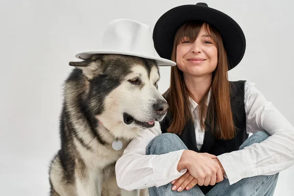 Γυναίκα και Σιβηρική Husky σκυλί ποζάρουν σε καπέλα — Φωτογραφία Αρχείου