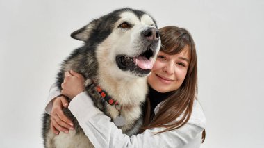Beyaz kadın tüylü Sibirya Husky köpeğine sarılıyor.