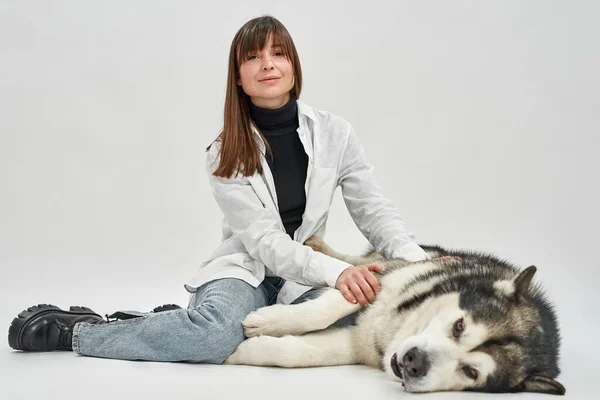 Ενήλικες καυκάσιος γυναίκα αγγίζοντας Σιβηρίας Husky σκυλί — Φωτογραφία Αρχείου