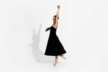 Beyaz arka planda dans eden genç balerin.