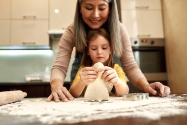 Hirl, büyükannenin yanında hamuru insan şeklinde tutuyor.