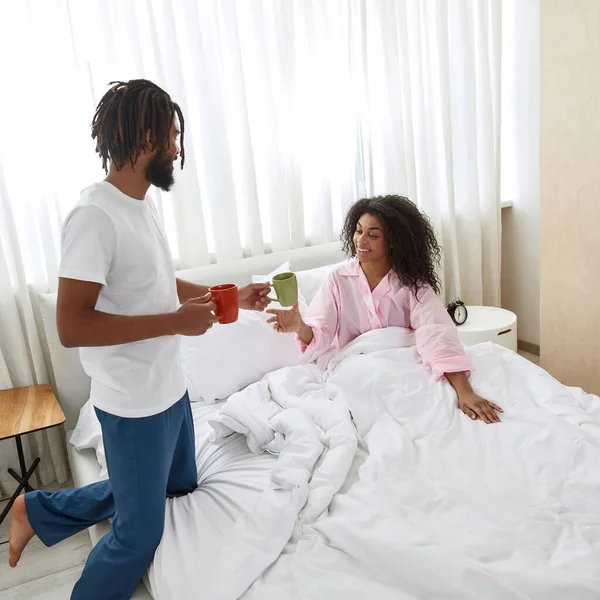 Adam yatakta kız arkadaşına çay veriyor.