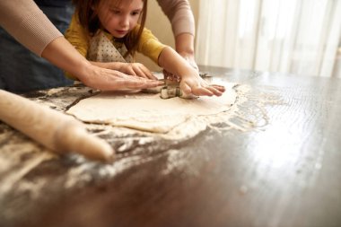 Küçük kız büyükannesiyle hamur kalıbı kullanıyor.