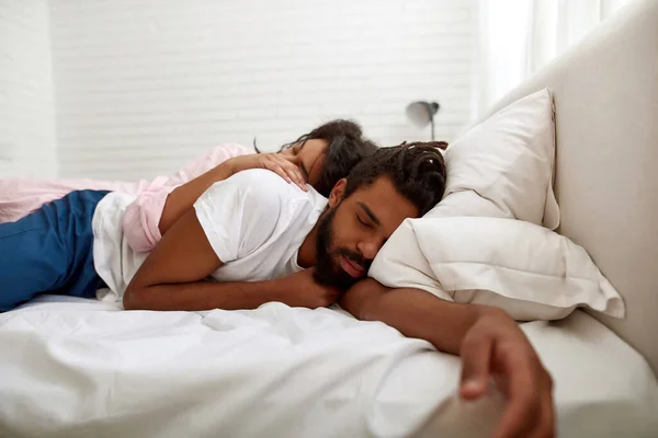 Svart par sover under filt på sängen hemma — Stockfoto