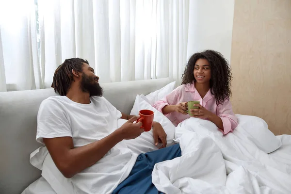 Joven pareja negra bebiendo té en la cama por la mañana —  Fotos de Stock
