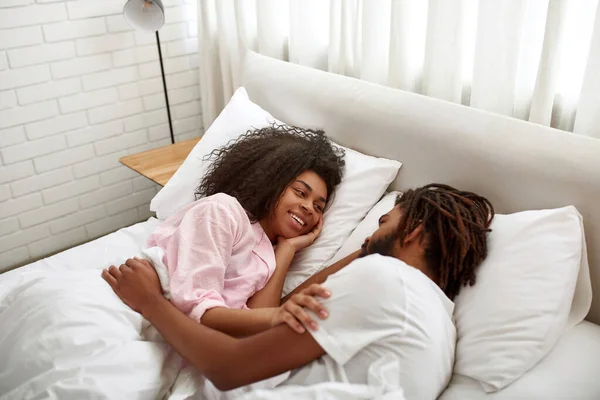 Unga par vilar och kramas på sängen på morgonen — Stockfoto