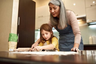 Gri saçlı büyükanne ile kurabiye yapan kız.