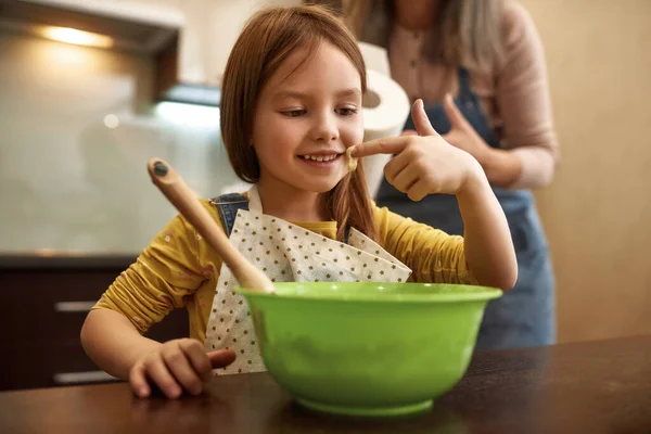 Mädchen schaut bei Großmutter mit Teig auf Finger — Stockfoto