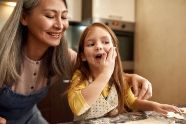 Kız, ninenin yanında krema gibi yüzüne un sür.