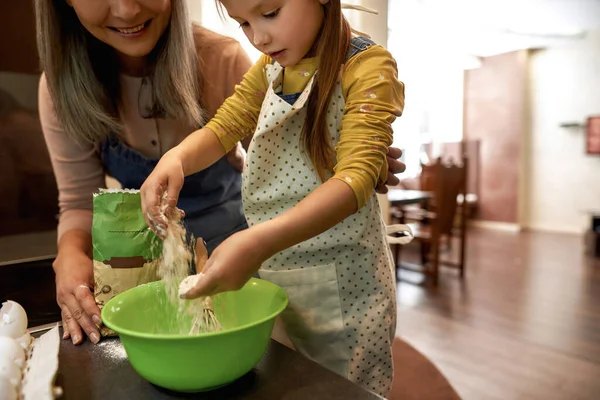 Kleines Mädchen gießt beim Kochen Mehl in Schüssel — Stockfoto