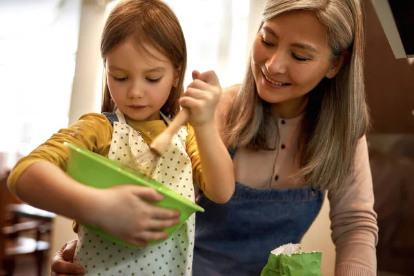 Flicka blanda något i skål med mormor — Stockfoto