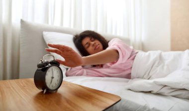 Genç kız, uyku sırasında çalar saati durdur.