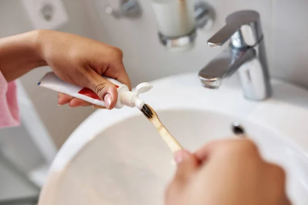 Manos de mujer negra ponen pasta de dientes en el cepillo de dientes — Foto de Stock