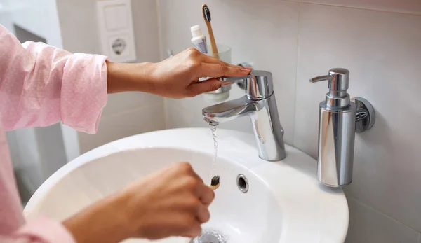 Mujer lavando cepillo de dientes con agua en lavabo — Foto de Stock