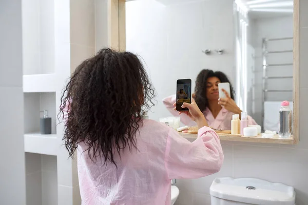 Chica tomar una foto en el teléfono inteligente de sí misma en el espejo — Foto de Stock