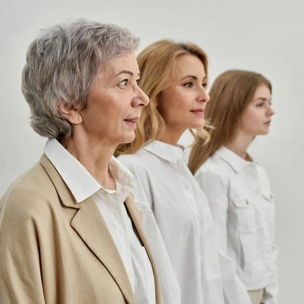 Fila de serias tres generaciones femeninas apartan la mirada —  Fotos de Stock