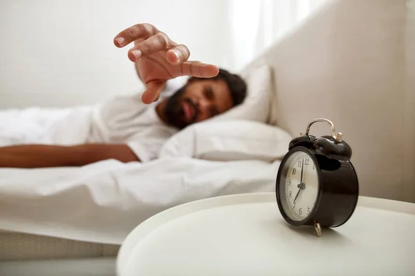 Man stoppar väckarklocka när man sover på sängen — Stockfoto