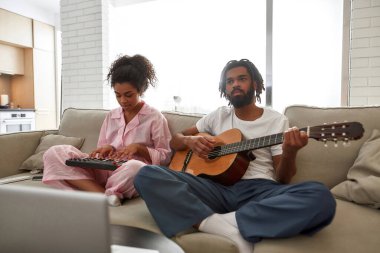 Siyah çift evde müzik enstrümanları çalıyor.