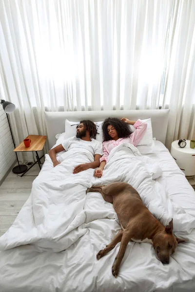 Giovane coppia nera e cane dormire sul letto a casa — Foto Stock