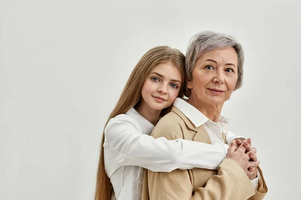 Enkelin umarmt ihre Oma auf weißem Hintergrund — Stockfoto