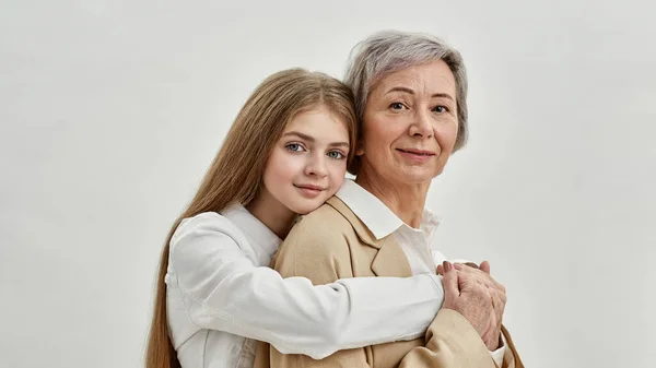 Enkelin umarmt ihre Oma im weißen Studio — Stockfoto