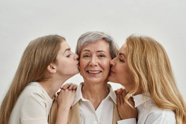 Genç bir kız ve yetişkin bir kadın yaşlı bir kadını öperler.
