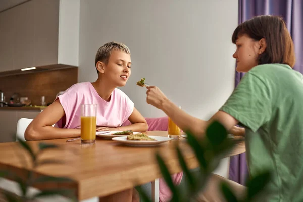 Girl feeding girlfriend during breakfast at home. — Fotografia de Stock