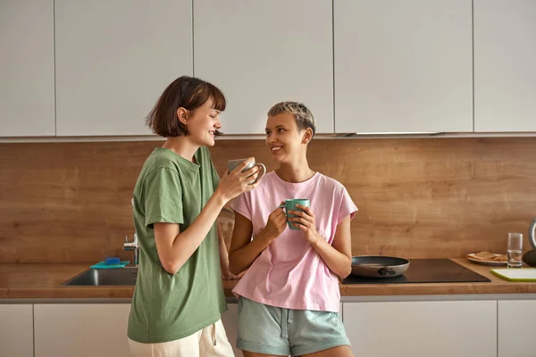 Lesbianas europeo pareja beber té en casa cocina — Foto de Stock