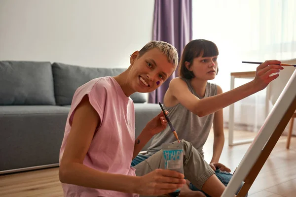 Girl look at camera while paint with girlfriend — Stock Photo, Image