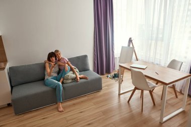 Evdeki kanepede televizyon izleyen genç lezbiyen kızlar.