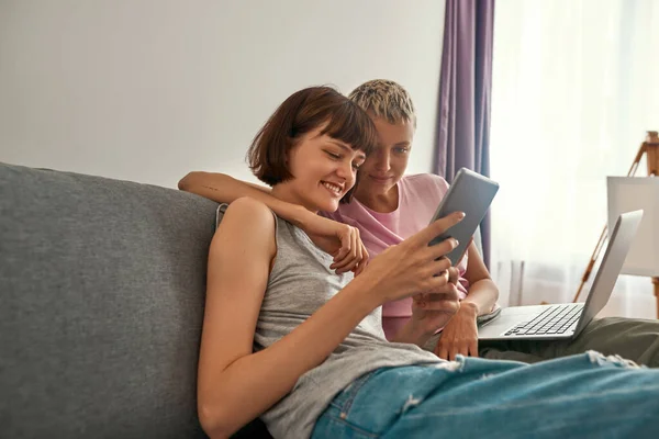 Lesbianas pareja viendo en digital tablet en sofá —  Fotos de Stock