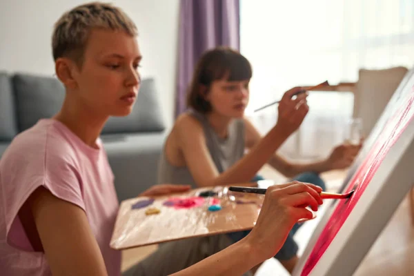 Blurred image of lesbian girls painting picture — Stock Photo, Image