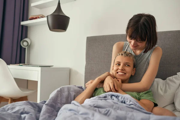 Jóvenes lesbianas abrazándose en la cama juntos en casa —  Fotos de Stock