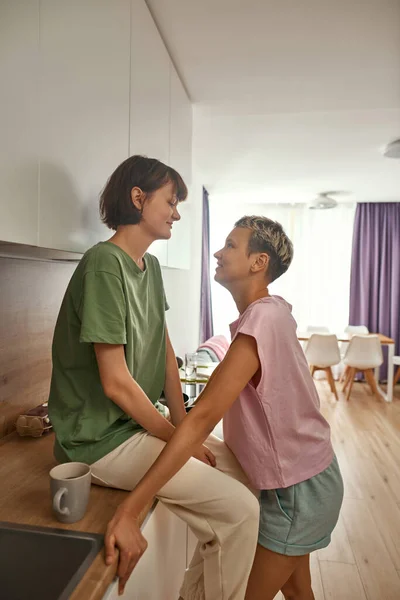 Lesbian girls look at each other at home kitchen — ストック写真