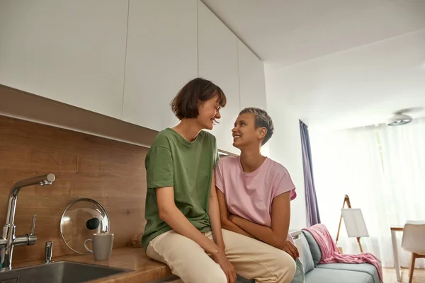 Las chicas sonrientes se miran en la cocina casera — Foto de Stock