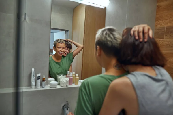 Las niñas riendo abrazan y miran en el espejo en el baño — Foto de Stock