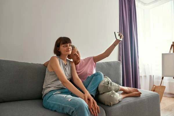 Lesbianas tomando selfie en smartphone en sofá —  Fotos de Stock