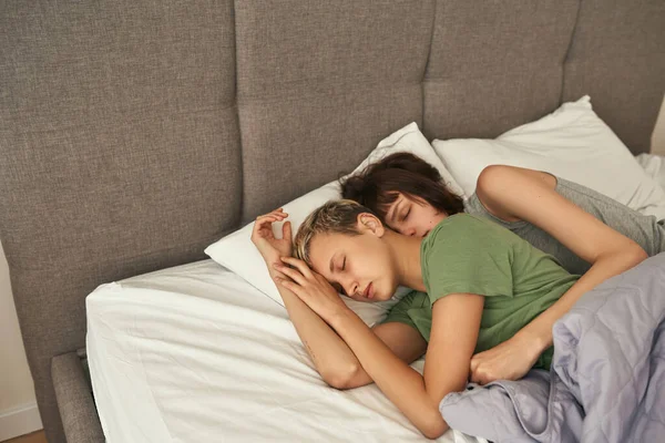 Caucasian lesbian couple sleeping on bed at home — стокове фото