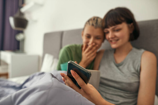 Selective focus of smartphone in hands of lesbians