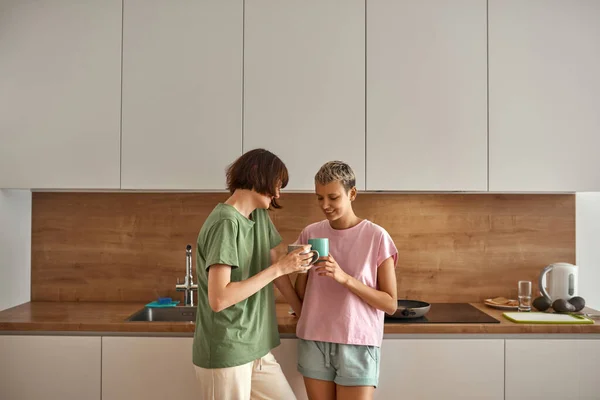 Chicas lesbianas jóvenes tomando té en casa cocina —  Fotos de Stock