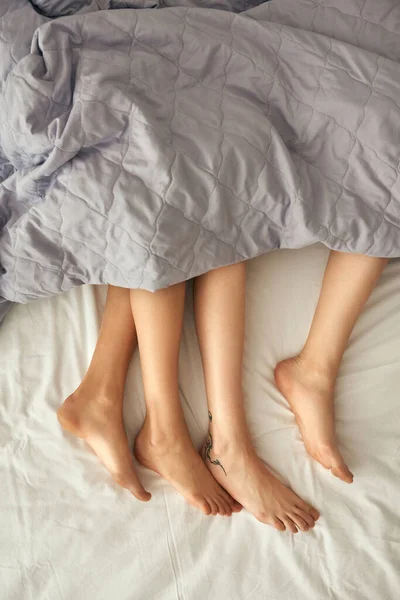 Ben av kvinnor under filt på sängen hemma — Stockfoto