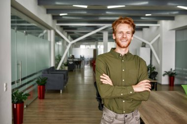 Kollarını kavuşturup kameraya bakan adam.