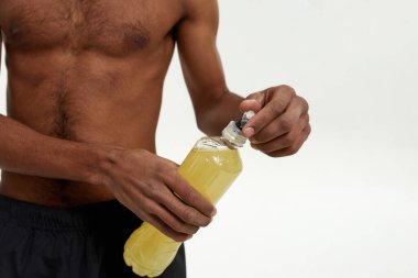 Siyah sporcu şişeyi spor içeceğiyle açıyor.