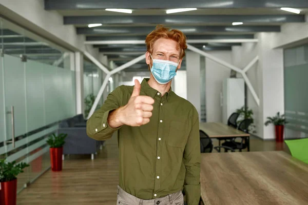 Joven caucásico hombre en máscara médica mostrar pulgar hacia arriba —  Fotos de Stock