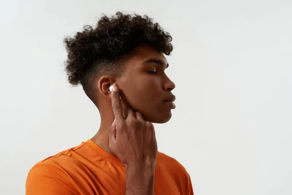 Thoughtful black man listening music in earphones — Stock Photo, Image
