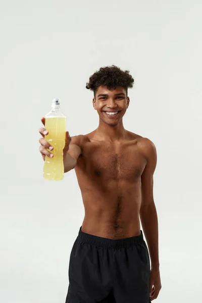 Black sportsman showing bottle with sport drink — Stock Photo, Image